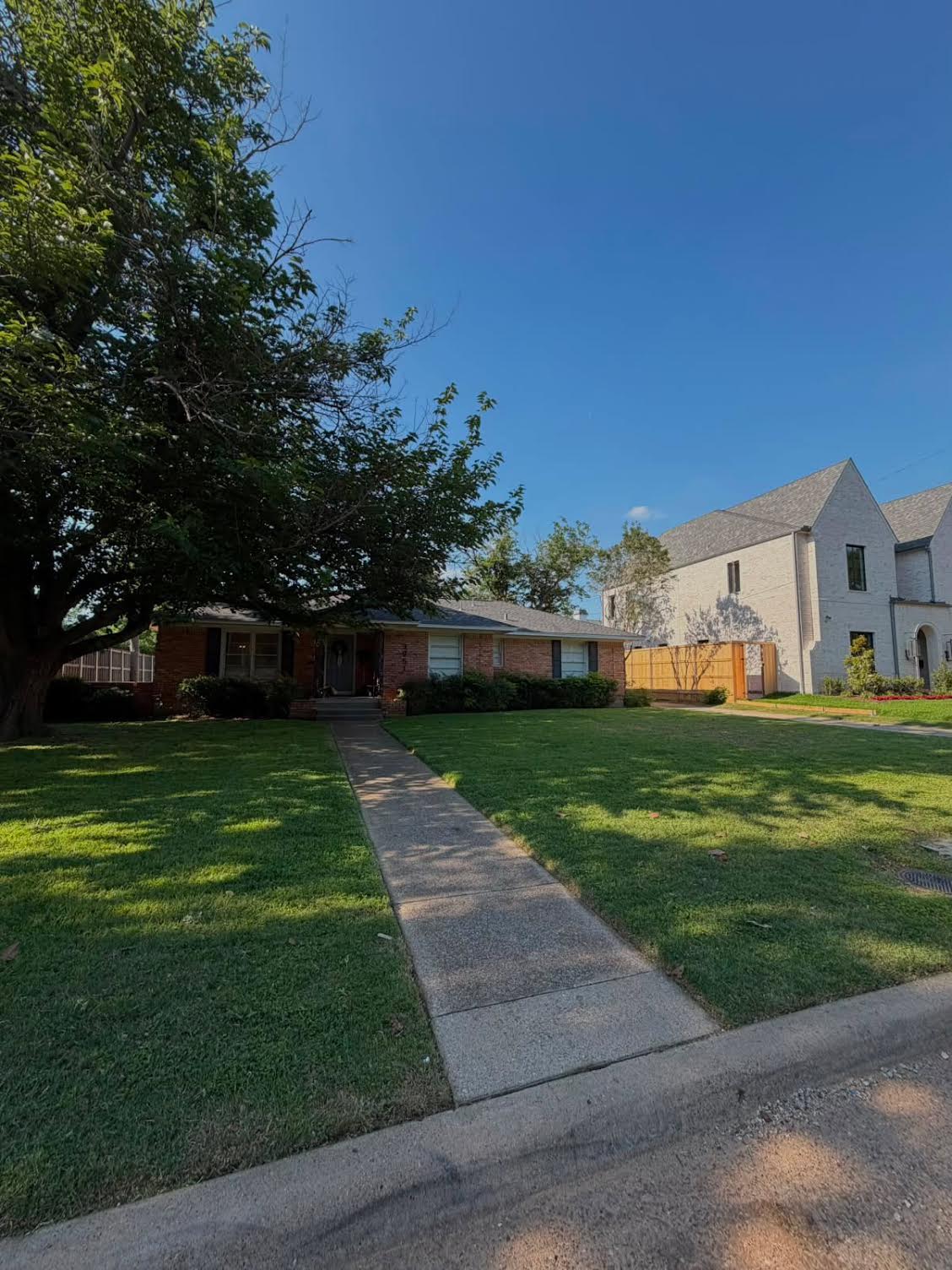 Shaded brick home lawn mowed and edged along the front walkway